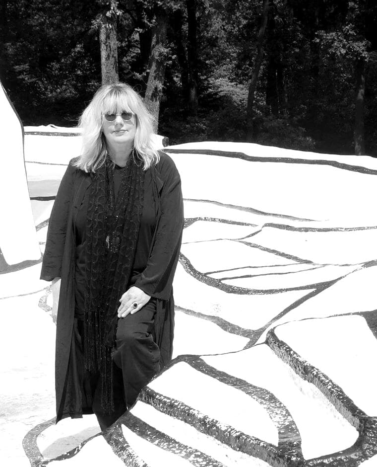 Jutta van den Berg in einer weissen Land-Art-Installation mit breiten schwarzen Linien, ganz in Schwarz gekleidet